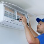 Ac Technician Wearing a Blue Uniform Uses a Hand Tool to Install an Air Conditioner.