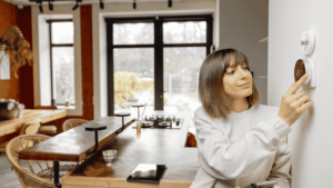 A person adjusts the temperature of their home with a modern thermostat.