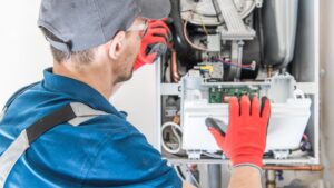 An HVAC professional inspects the internal workings of a heater.