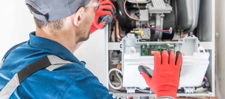 An HVAC professional inspects the internal workings of a heater.