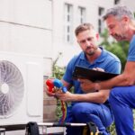Two HVAC technicians inspect the readings on a device.